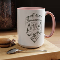 White ceramic mug with a contrasting handle and interior, featuring a minimalist design of Yellowstone National Park with mountains, trees, and a river.