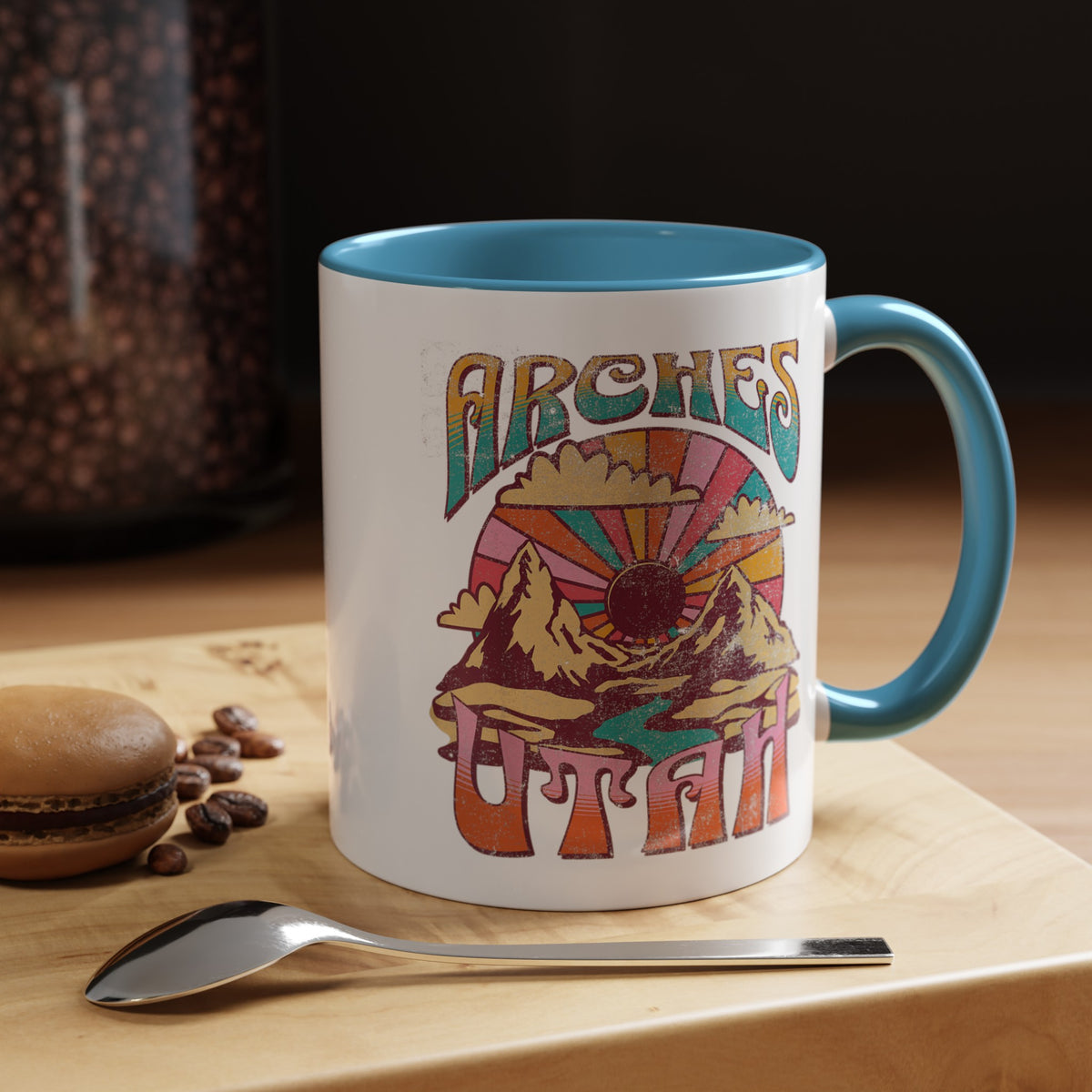 White ceramic mug with a contrasting handle and interior, featuring a colorful scenic design of Arches National Park in Utah.