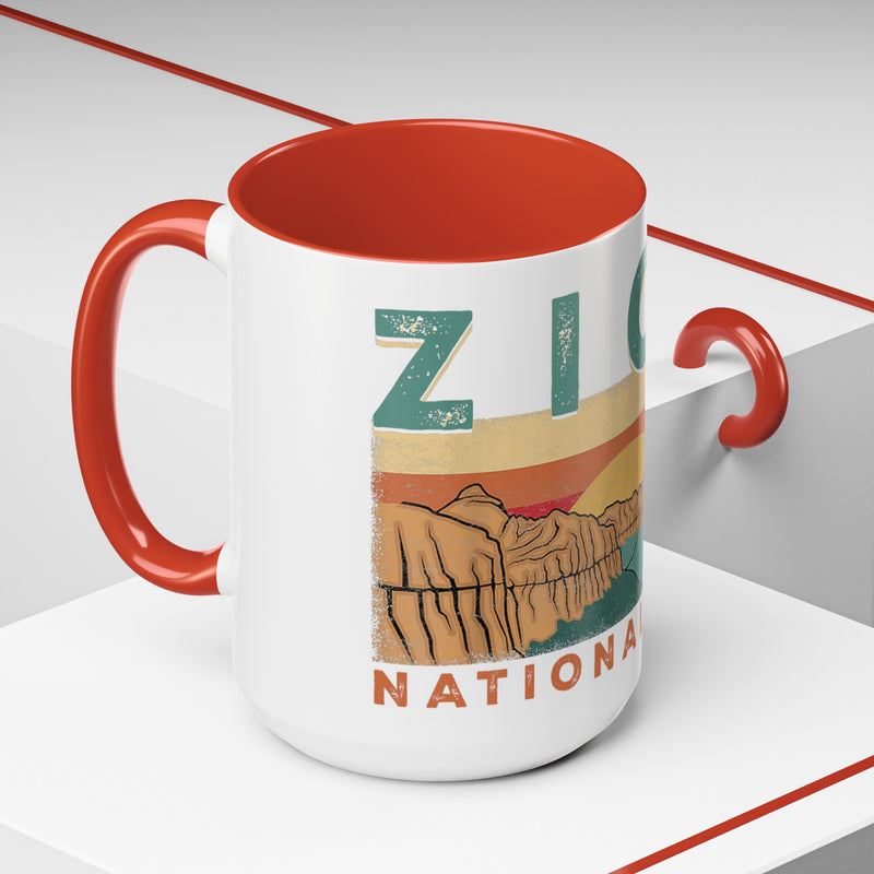 White ceramic mug with contrasting handle and interior, featuring a sunset landscape design of Zion National Park.