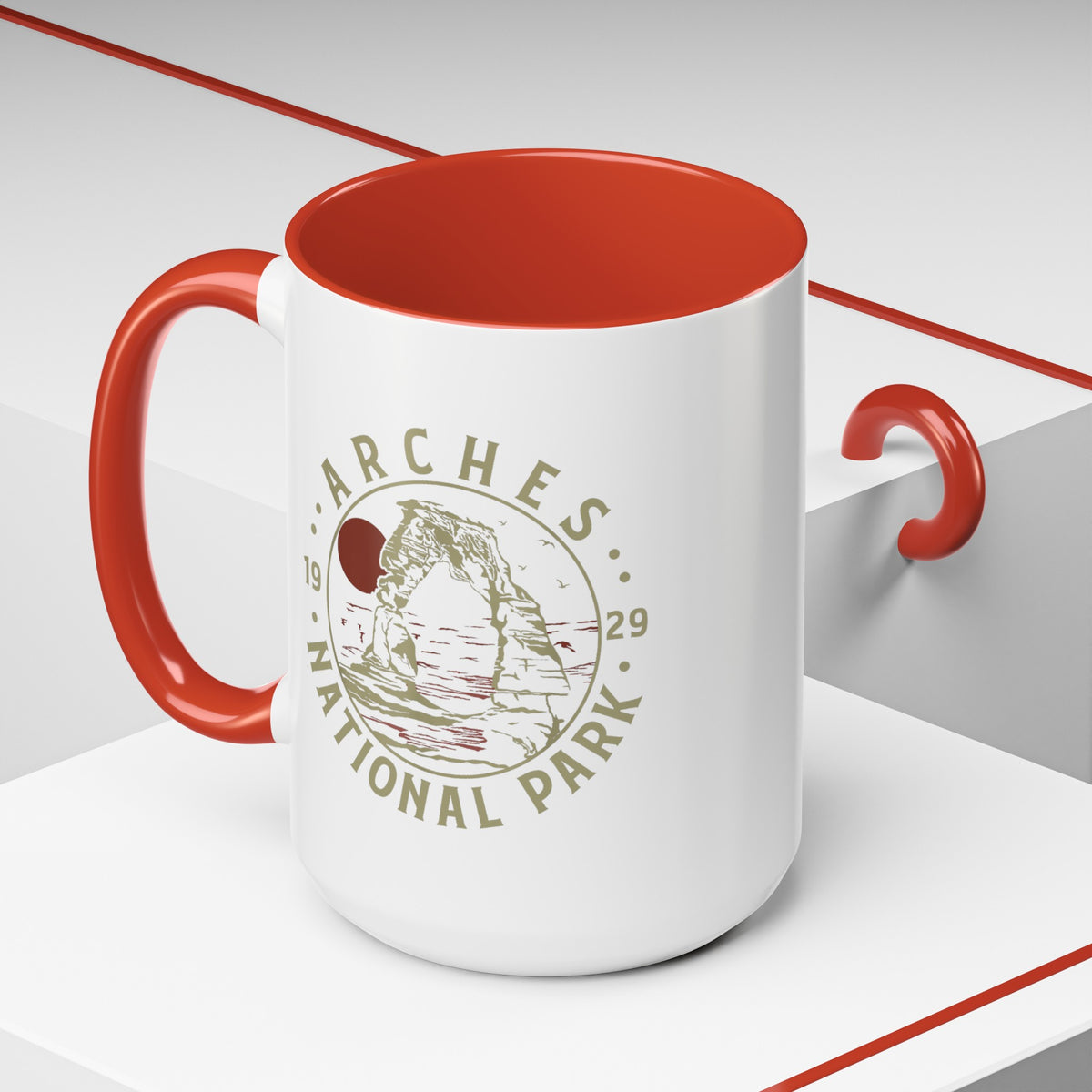 White ceramic mug with a contrasting handle and interior, featuring a design of Arches National Park with Delicate Arch and a sun graphic.