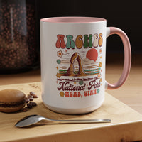 15 oz pink Arches National Park souvenir mug featuring a scenic design with mountains, arches, and a colorful sunset from Utah.