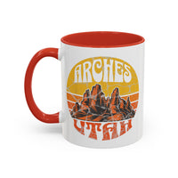 11 oz red ceramic mug with a contrasting handle and interior, featuring a vibrant design of Arches National Park in Utah, showcasing the park's iconic rock formations.