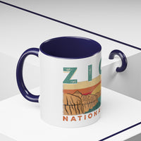 White ceramic mug with contrasting handle and interior, featuring a sunset landscape design of Zion National Park.