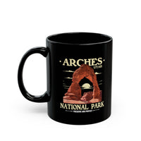 Black ceramic coffee mug featuring a detailed design of Arches National Park in Utah, perfect for coffee or tea lovers.