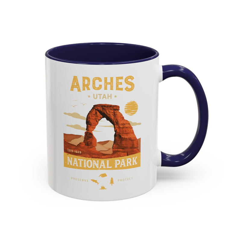 White 11 oz ceramic coffee mug with a navy handle, featuring a detailed design of Arches National Park, Utah. Perfect for coffee or tea lovers.