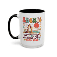 15 oz black Arches National Park souvenir mug featuring a scenic design with mountains, arches, and a colorful sunset from Utah.