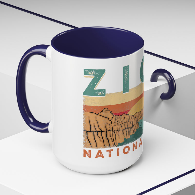 White ceramic mug with contrasting handle and interior, featuring a sunset landscape design of Zion National Park.