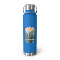 A pebble blue double-wall stainless steel water bottle featuring a scenic design inspired by North Cascades National Park, showcasing mountains and pine trees.