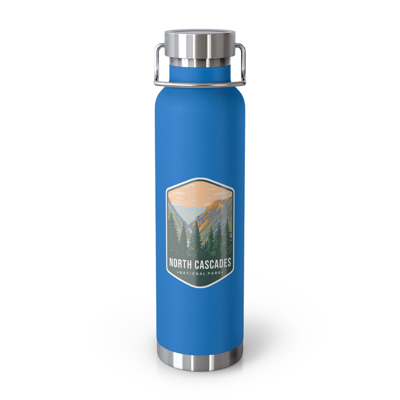 A pebble blue double-wall stainless steel water bottle featuring a scenic design inspired by North Cascades National Park, showcasing mountains and pine trees.