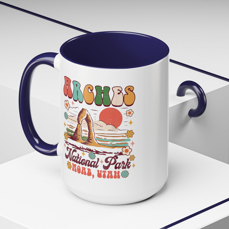 15 oz navy Arches National Park souvenir mug featuring a scenic design with mountains, arches, and a colorful sunset from Utah.