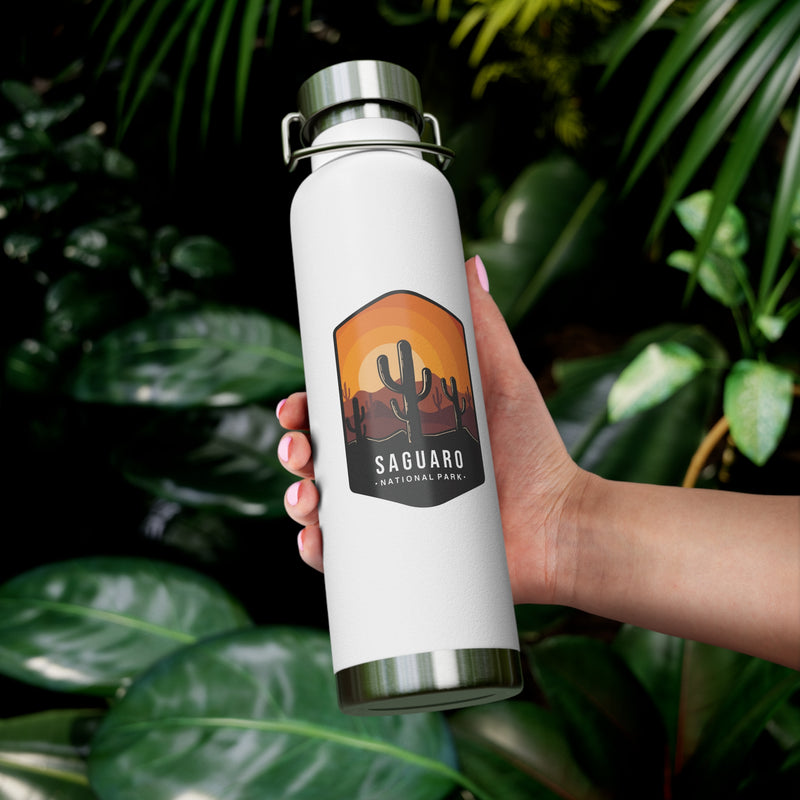 White stainless steel water bottle featuring a design of Saguaro National Park with cactus and sunset scenery.