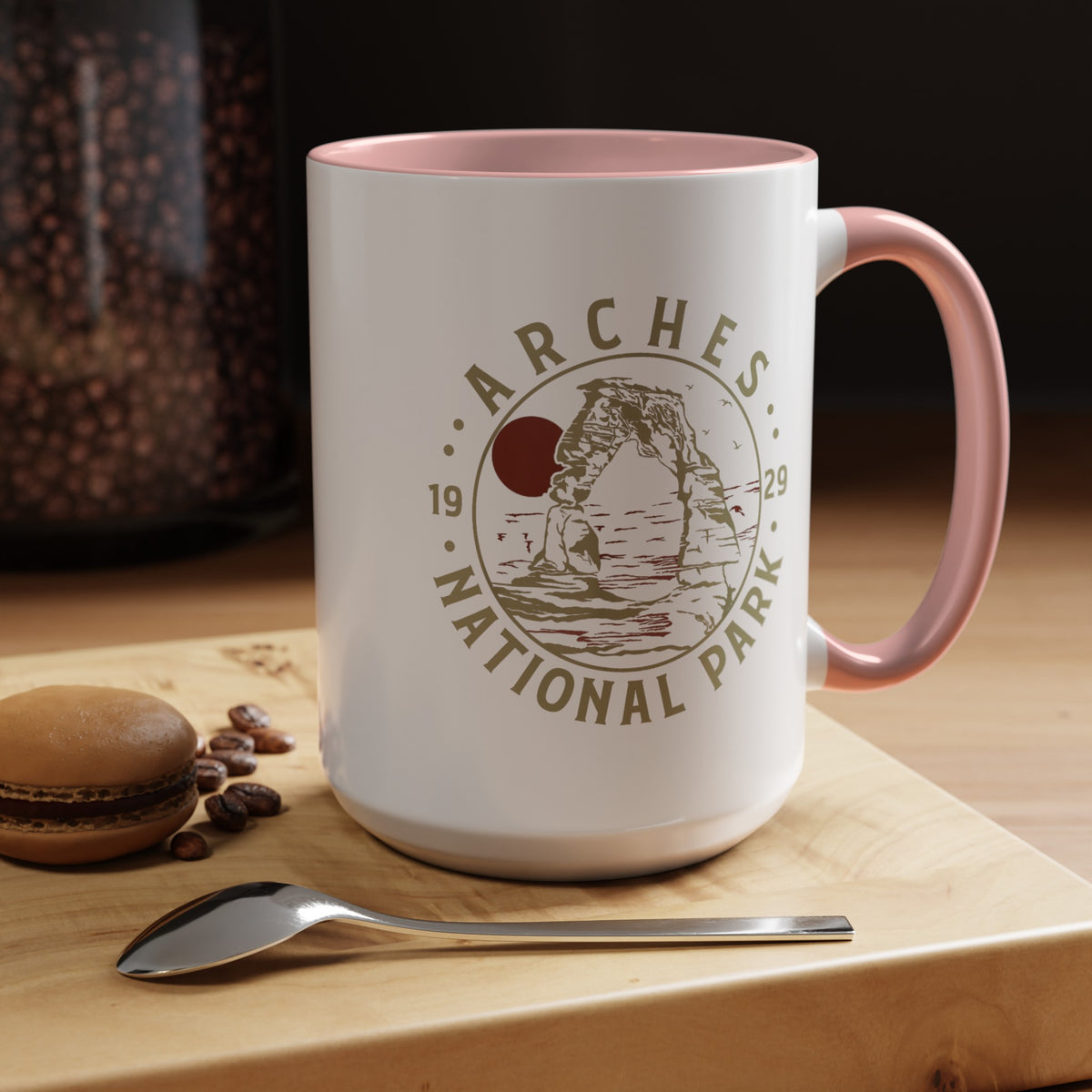 White ceramic mug with a contrasting handle and interior, featuring a design of Arches National Park with Delicate Arch and a sun graphic.