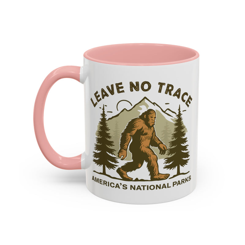 11 oz pink Bigfoot souvenir mug with "Leave No Trace" text, trees, and mountains in the background, from America's National Parks.