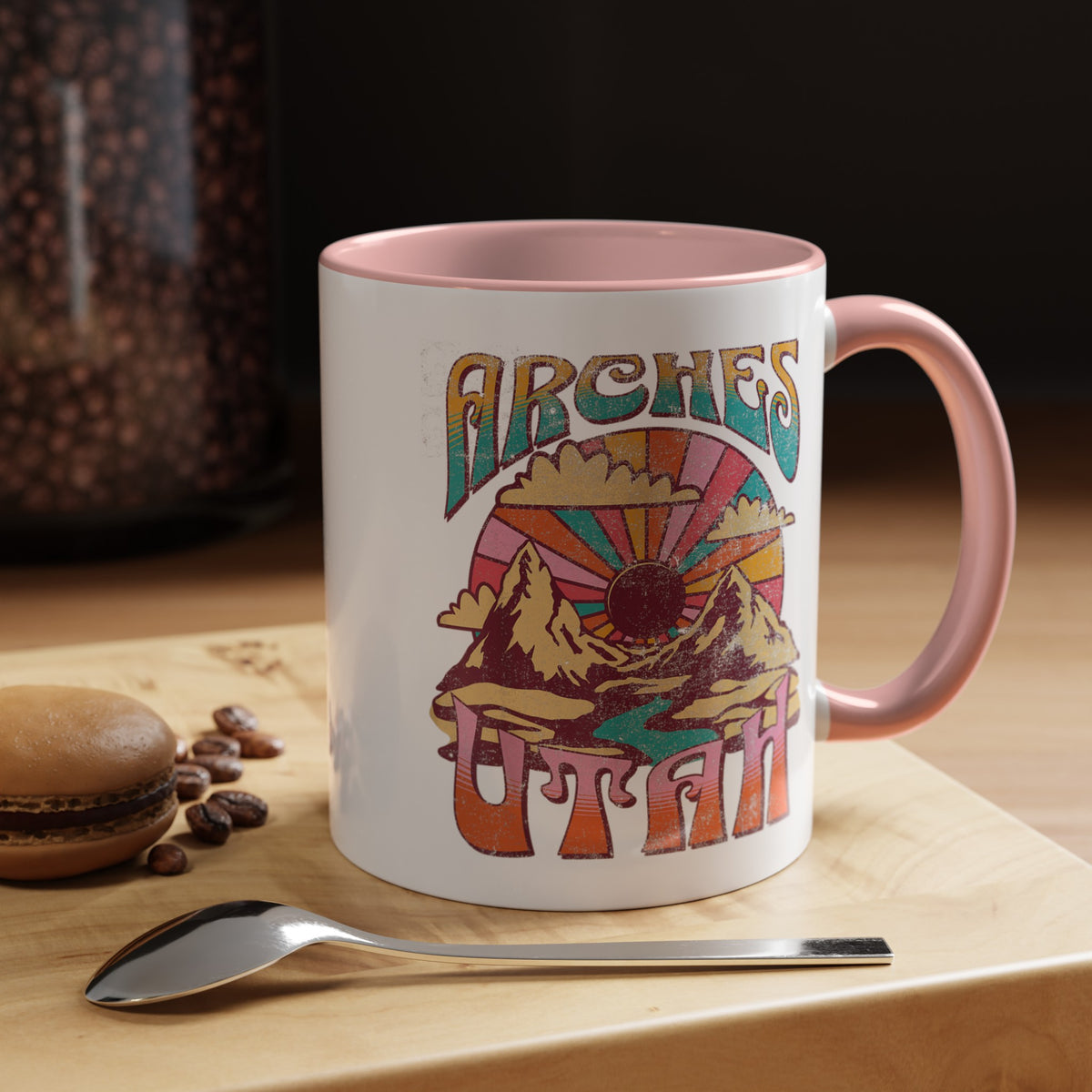 White ceramic mug with a contrasting handle and interior, featuring a colorful scenic design of Arches National Park in Utah.