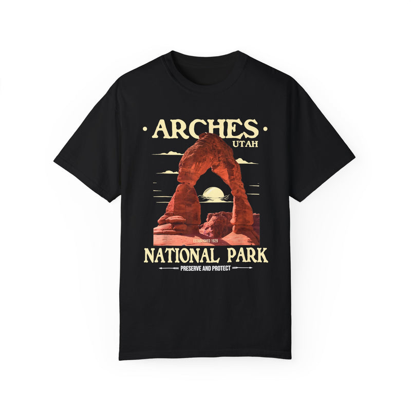 T-shirt featuring a scenic design of Arches National Park in Utah with a prominent arch and sunset background.