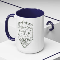 White ceramic mug with a contrasting handle and interior, featuring a minimalist design of Yellowstone National Park with mountains, trees, and a river.