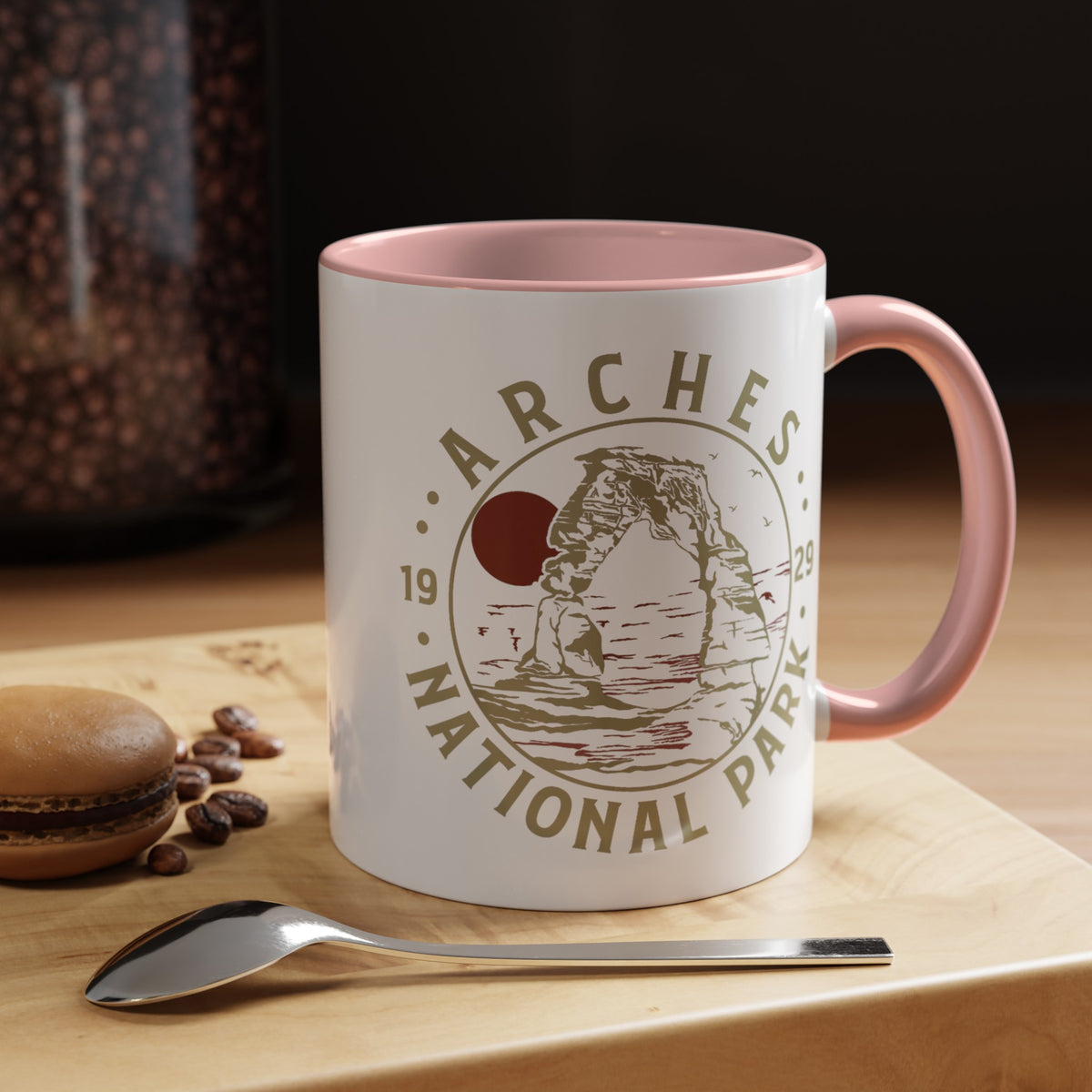 White ceramic mug with a contrasting handle and interior, featuring a design of Arches National Park with Delicate Arch and a sun graphic.