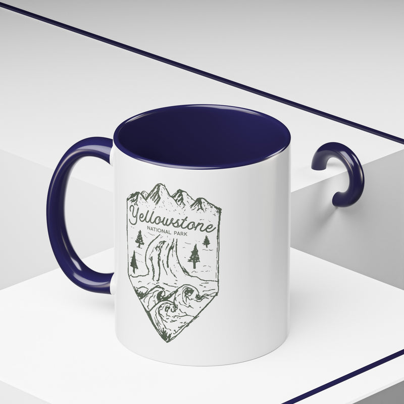 White ceramic mug with a contrasting handle and interior, featuring a minimalist design of Yellowstone National Park with mountains, trees, and a river.