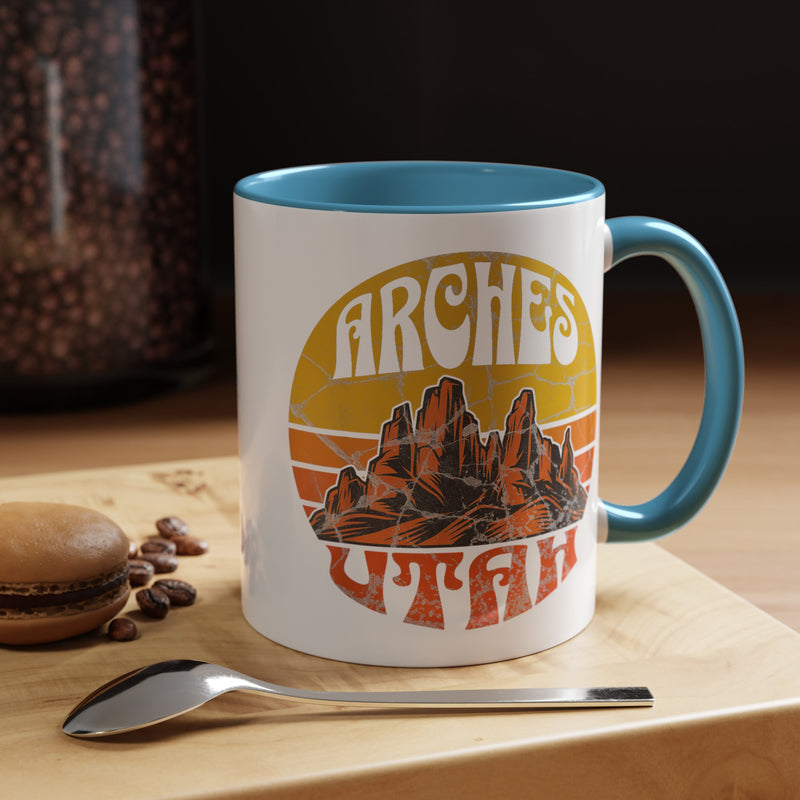 11 oz light blue ceramic mug with a contrasting handle and interior, featuring a vibrant design of Arches National Park in Utah, showcasing the park's iconic rock formations.