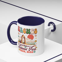 11 oz navy Arches National Park souvenir mug featuring a scenic design with mountains, arches, and a colorful sunset from Utah.