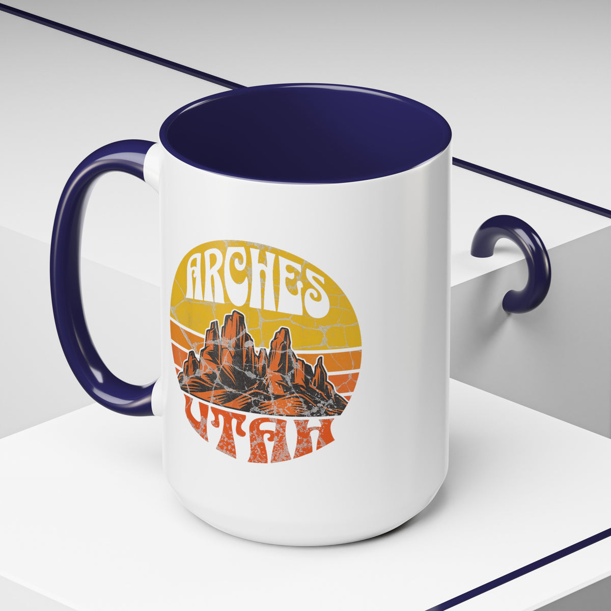 15 oz navy ceramic mug with a contrasting handle and interior, featuring a vibrant design of Arches National Park in Utah, showcasing the park's iconic rock formations.